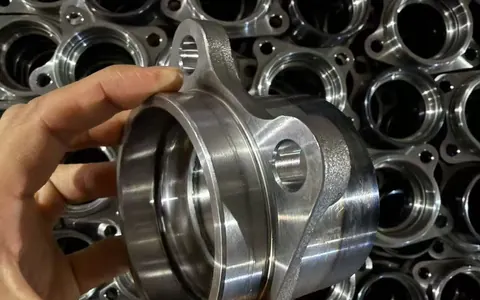 CHKZ technician inspecting a wheel hub blank against rows of machined hubs in the production cell